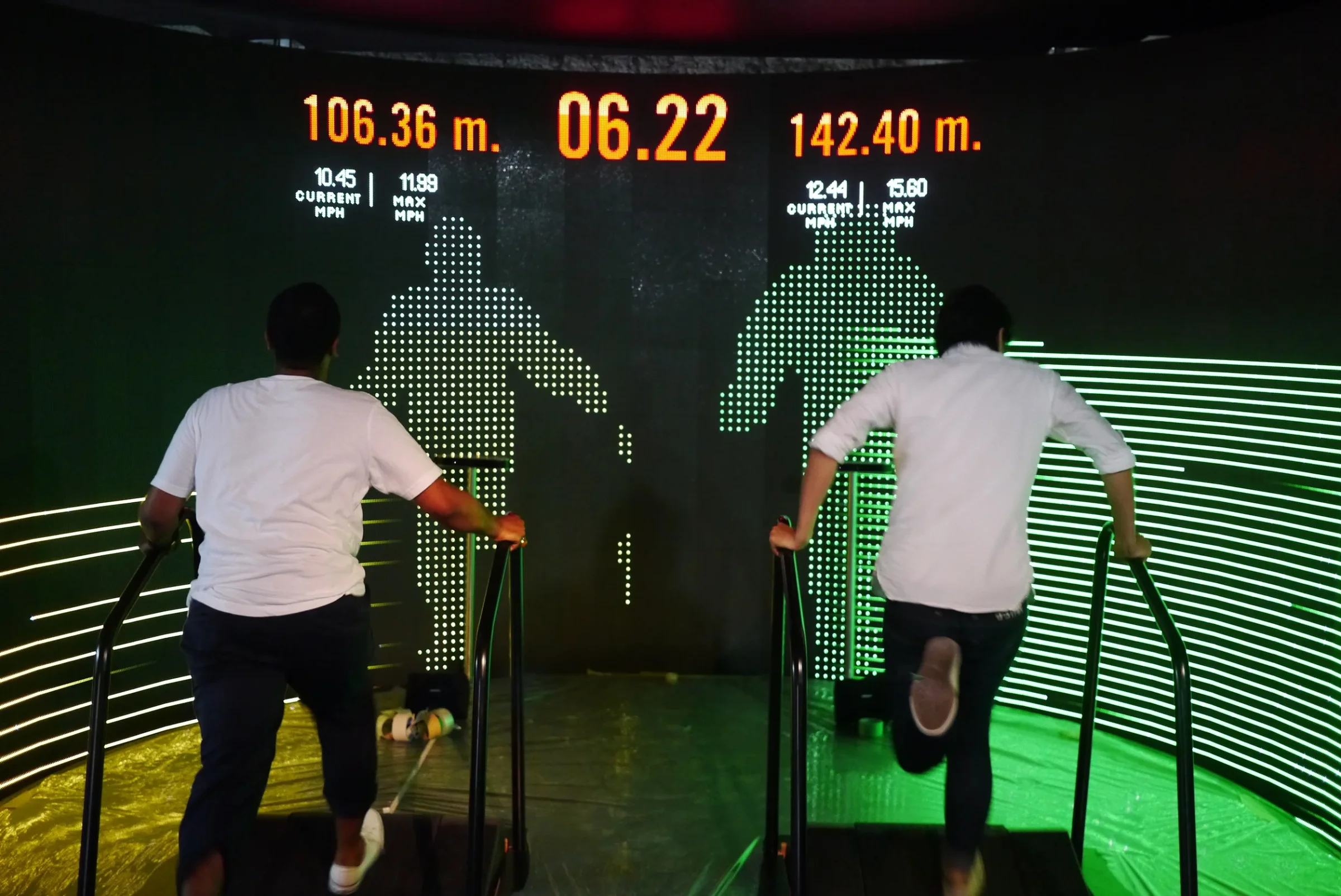 The two user-powered curved treadmills facing the curved LED wall game display